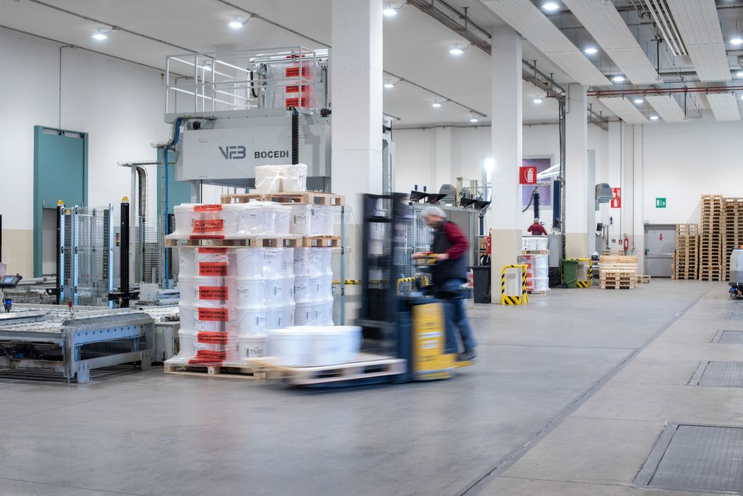 Gabelstapler in einer hellen Lagerhalle mit Paletten und Stapelbehältern